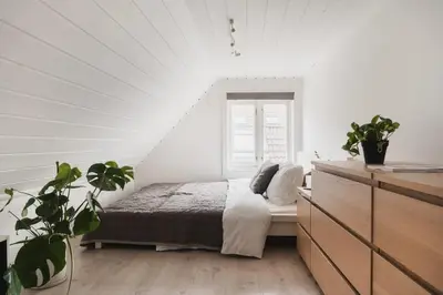 a white bedroom with a bed and a window at Cozy loft with king bed in the middle of town in Bergen