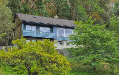 a large house with a blue roof in the forest at Awesome Home In Eidfjord With House Sea View in Eidfjord