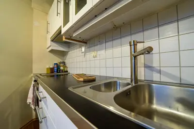 a stainless steel sink in a kitchen with white tiles at Penthouse in Bergen