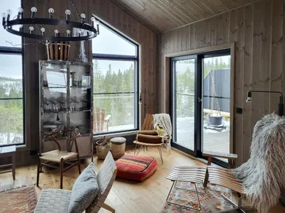 a living room with wooden walls and large windows at Modern Cabin In Norefjell With Sauna in Noresund