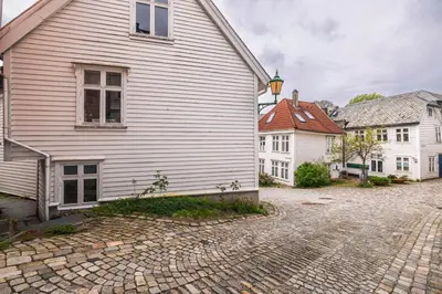 a white house on a cobblestone street next to buildings at Modern Apartment in the Heart of Bergen in Bergen