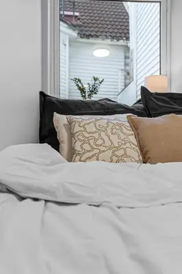 a white bed with pillows and a window at Modern Apartment in the Heart of Bergen in Bergen