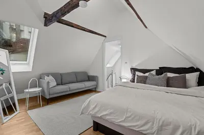 a white bedroom with a bed and a couch at Large Historic Apartment in the best part of Bergen in Bergen