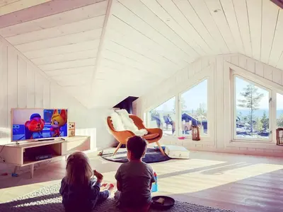 two children sitting on the floor in a living room watching tv at Family Cabin With Views In Lygnalia in Jaren