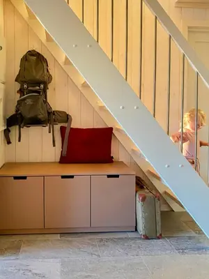 a man sitting under the stairs with a laptop at Family Cabin With Views In Lygnalia in Jaren
