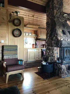 a living room with a stone fireplace and a chair at Authentic Cabin Overlooking Lake Møsvann in Rjukan