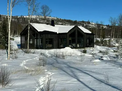 a log cabin with snow on the roof in the snow at Mountain Cabin With Beautiful Lake View in Hemsedal