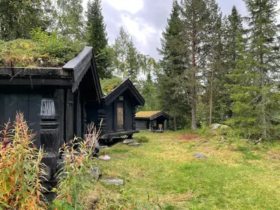 a small black house in the middle of a field at Traditional Log Cabin By Lake Seljord in Seljord