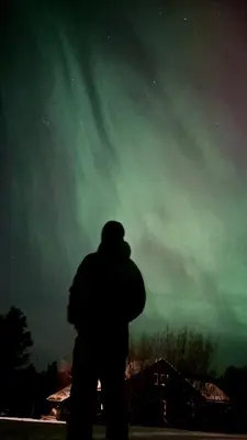a man standing in front of a green sky at Modern and cozy mountain cabin - panoramic view! in Torvetjørn