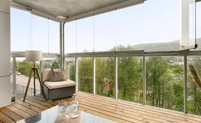 a living room with large windows and a chair at Solheimslien in Bergen