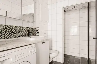 a white bathroom with a toilet and a sink at Leiligheter i sentralt Bergenshus in Bergen