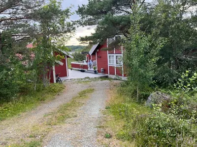 a dirt road in front of a red house at Stor hytte med praktfull havutsikt in Lysøysund