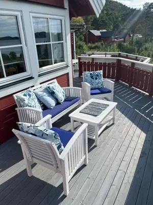 a porch with three chairs and a table and a table and benches at Stor hytte med praktfull havutsikt in Lysøysund