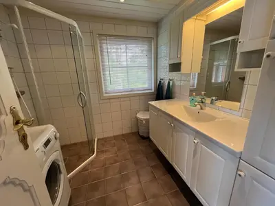 a bathroom with a sink and a washing machine at Stor hytte med praktfull havutsikt in Lysøysund