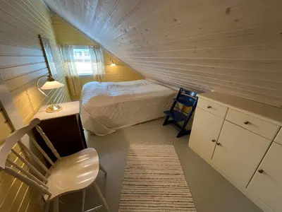 a small bedroom with a bed and a chair at Stor hytte med praktfull havutsikt in Lysøysund