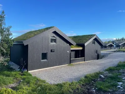 a gray building with a grass roof on a road at Fjellro Budor - ski in ski out in Løten