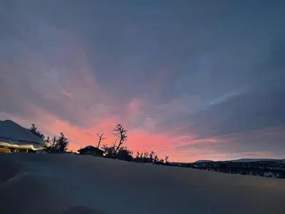 a sunset over a snowy field with trees and a sky at Modern Cabin With Views Of Langsua National Park in Etnedal