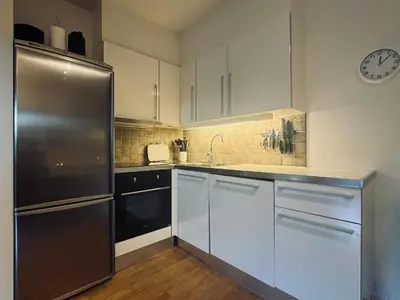 a kitchen with white cabinets and a stainless steel refrigerator at Central Apartment in Geilo in Geilo