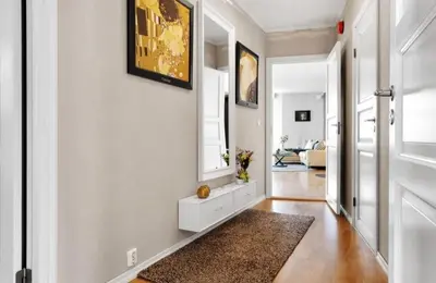 a hallway with a white wall with a mirror and a rug at Central, lovely apartment with a unique view in Bergen