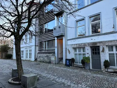 a cobblestone street in front of a white building at Central Apt - Steps to Fish Market and Bryggen in Bergen