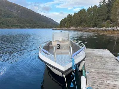 a small boat tied to a dock on a lake at Great House with a panoramic view in Storsæter