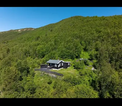 a house in the middle of a green hill at Charming cabin with lovely views at Geilo in Geilo
