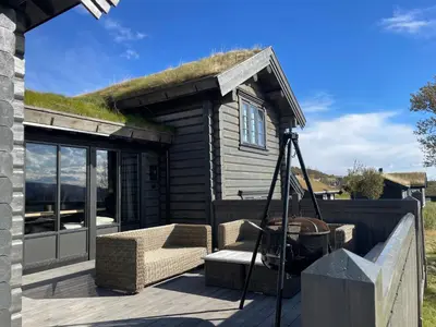 a log cabin with a grass roof with a bench at Fjellhytte Med 4 Soverom, Sauna, Peis Og Terrasse in Beitostøl