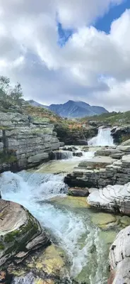 a river with rapids on the side of a waterfall at Kvamsfjellet - Rondane in Nord-Fron