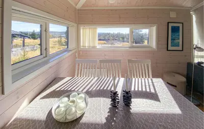 a dining room with a table and two windows at 3 Bedroom Cozy Home In Sjusjøen in Sjusjøen