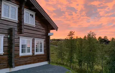 a wooden house with a sunset in the background at Cozy Home In Rauland With Wifi in Rauland