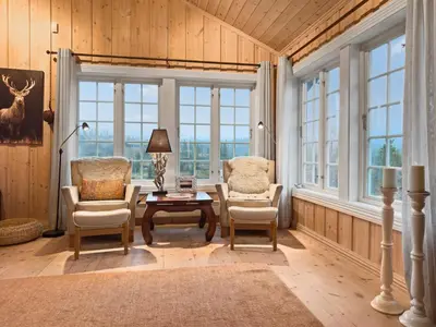 a living room with two chairs and a table and windows at Mountain cabin in Aurdal Fireplace Sauna 1000 meters above sea level in Aurdal
