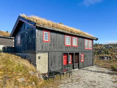 a black barn with red windows and a grass roof at Mountain cabin in Aurdal Fireplace Sauna 1000 meters above sea level in Aurdal