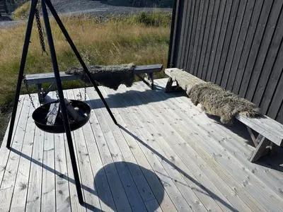 a dog laying on a deck next to a bench at New cabin in Slåseterlia at Skeikampen in Svingvoll