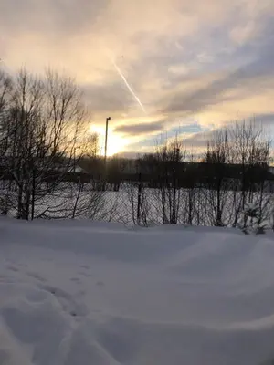 a snow covered field with trees and a sunset at Compact living with all you need, close to the centre! in Røros