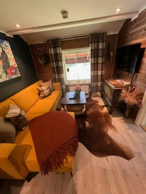 a living room with a yellow couch and a table at Charming apartment with lodgefeeling in Hemsedal