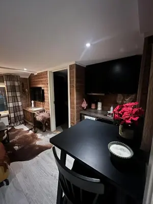 a living room with a black table and a kitchen at Charming apartment with lodgefeeling in Hemsedal