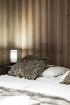 a bed with a pillow and a table with a lamp at Nyørk Chalet, Hemsedal in Hemsedal