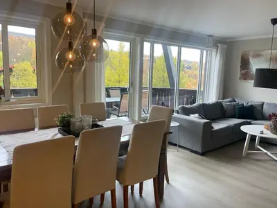 a dining room and living room with a table and chairs at Hjemmekoselig Toppleilighet I Sentrum in Beitostøl