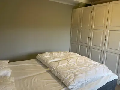 an unmade bed in a bedroom with white cabinets at Hjemmekoselig Toppleilighet I Sentrum in Beitostøl