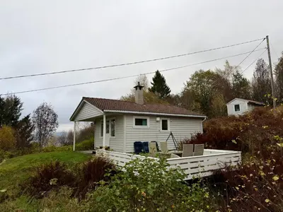 a small white house with a porch in a field at Fjordview retreat in Hamre