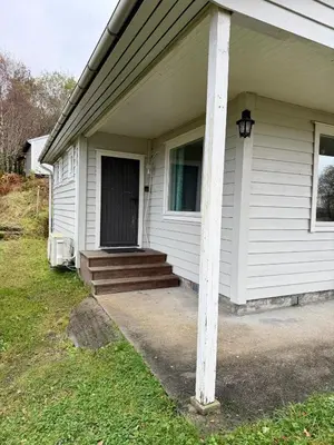 a white house with a porch and a column at Fjordview retreat in Hamre
