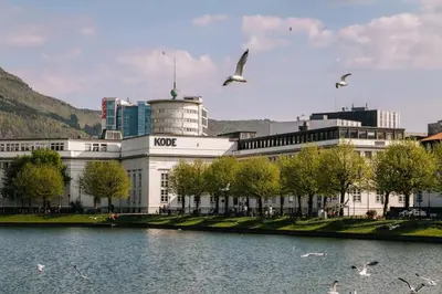a large white building with birds flying over a lake at Barfot Apartment - Bergen City center in Bergen