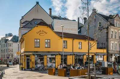 a yellow building with people sitting in front of it at Barfot Apartment - Bergen City center in Bergen