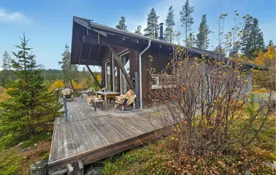 a cabin with a wooden deck in the woods at Nice Home In Tinn Austbygd With Sauna in Luråsgrendi