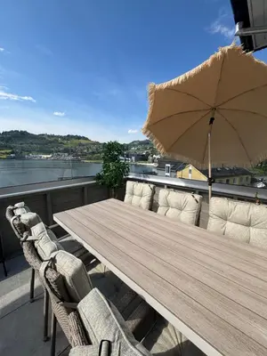 a wooden table with chairs and an umbrella on a balcony at Toppleilighet i sentrum av øystese in Kvam