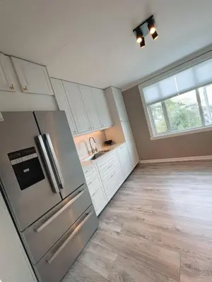 a kitchen with a stainless steel refrigerator and a window at Toppleilighet i sentrum av øystese in Kvam