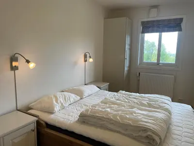 a bedroom with a bed with white sheets and a window at Leilighet For 4 I Sentrum in Beitostøl