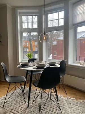 a dining room with a table and chairs and windows at Nice apartment super central at Solsiden in Trondheim