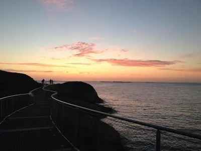 a sunset over the ocean with people on the rocks at Strand farm, sea view and boat rental in Averoy