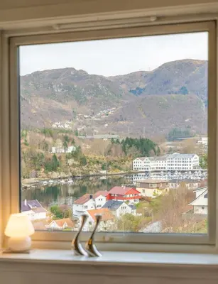 a window with a view of a town and mountains at Small house close to nature and city in Bergen